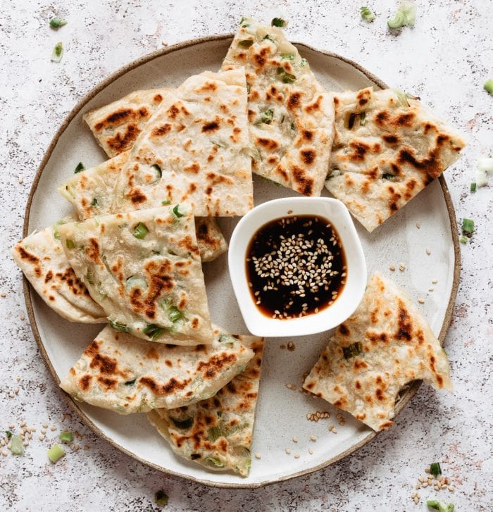 slices of green onion scallion pancakes on a plate with dipping sauce