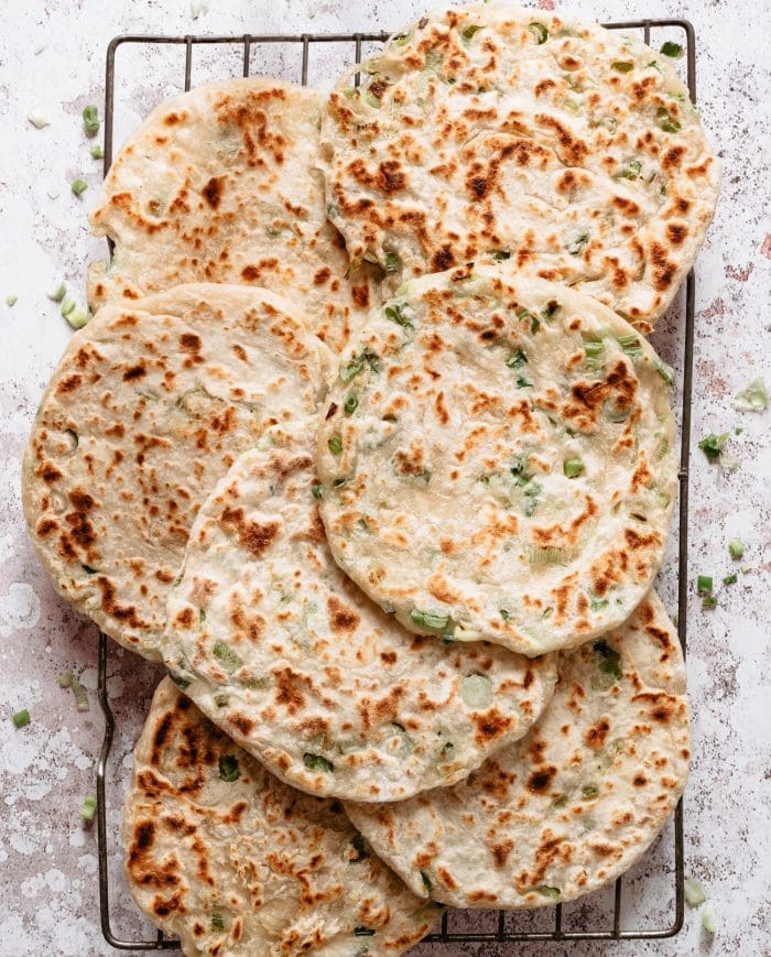 several scallion green onion pancakes laid out on a cooling rack