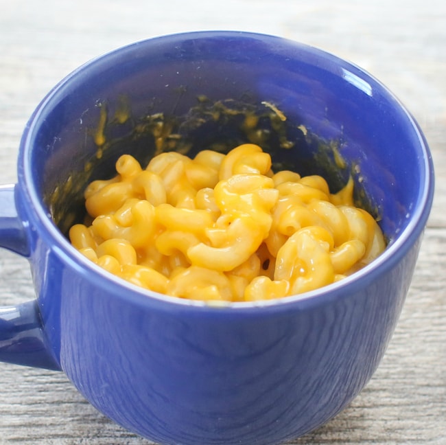 a close-up photo of macaroni and cheese in a blue mug
