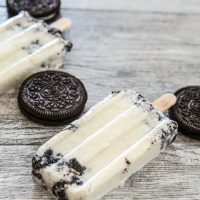 cookies and cream ice pops lying down next to Oreos