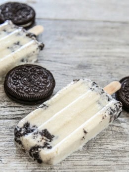 cookies and cream ice pops lying down next to Oreos