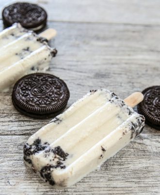 cookies and cream ice pops lying down next to Oreos