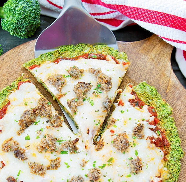 close-up of broccoli crust pizza with a slice being taken out