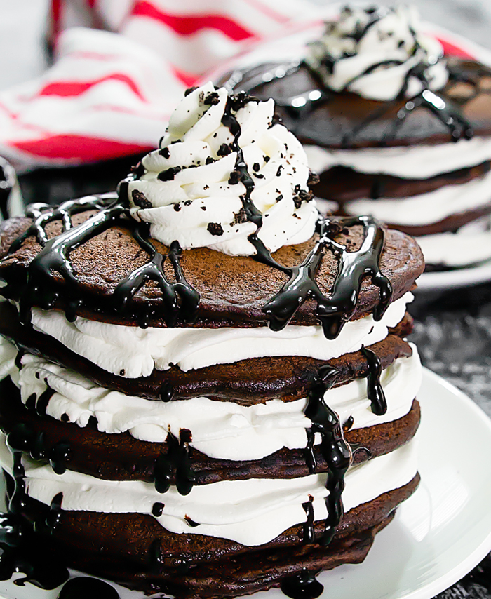a stack of oreo pancakes with whipped cream and chocolate syrup