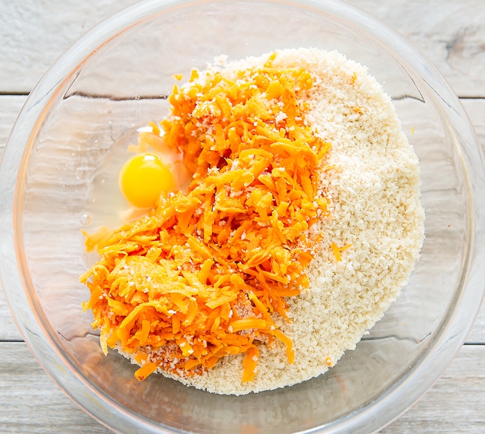 step by step photo showing shredded sweet potatoes, breadcrumbs, and egg in a bowl