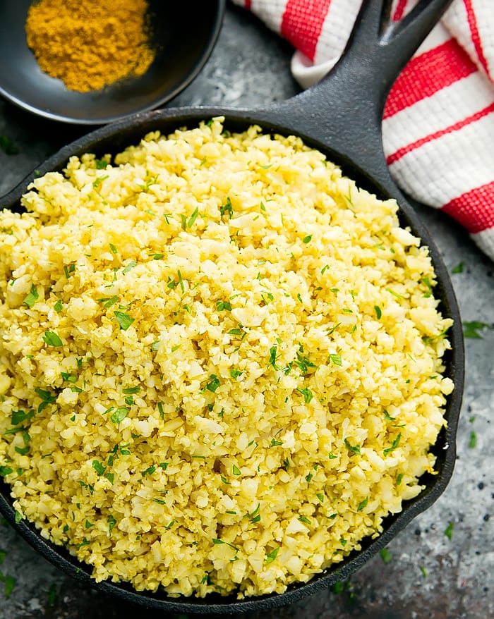 overhead photo of curry cauliflower rice in a black skillet