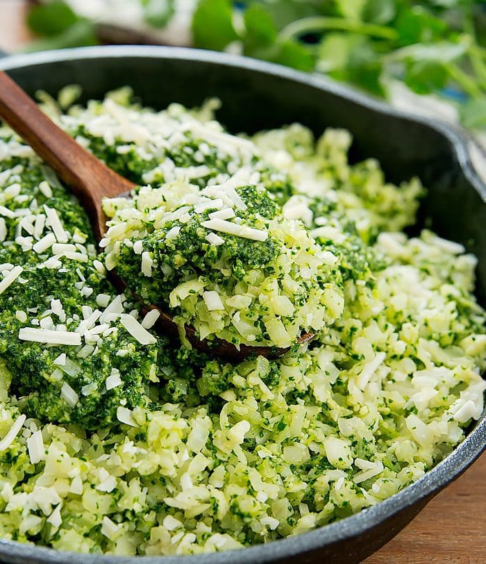 a close-up shot of a wooden spoon with a scoop of pesto cauliflower rice
