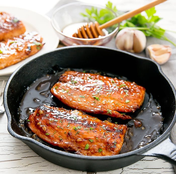 two pieces of Honey Garlic Salmon in a black skillet