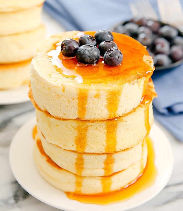 a stack of Japanese souffle pancakes topped with syrup and fresh blueberries