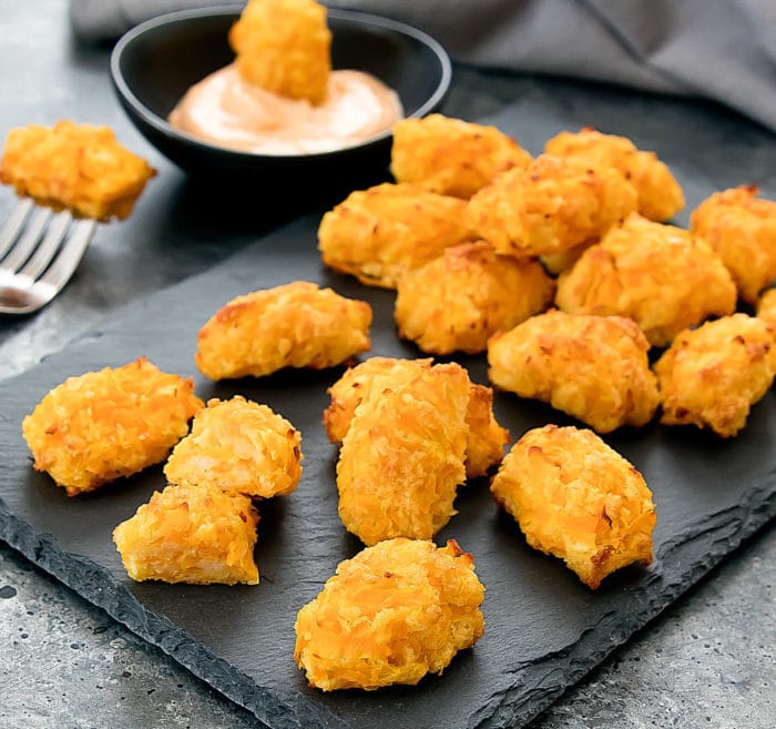Close-up shot of butternut squash tots on a slate board with dipping sauce