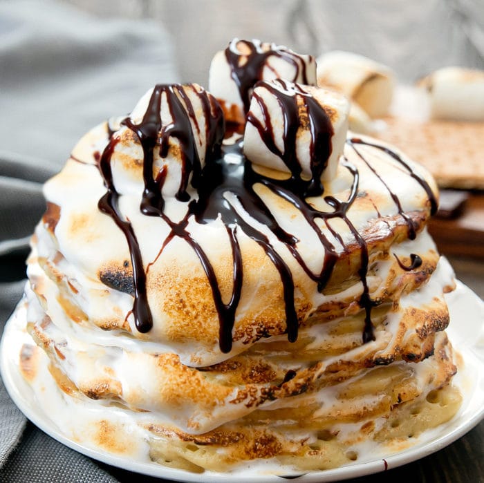 a close-up of s'mores pancakes topped with marshmallows and chocolate syrup