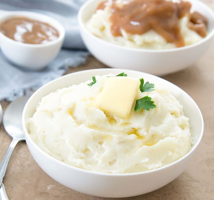 Instant Pot mashed potatoes in a white bowl with a pat of butter on top