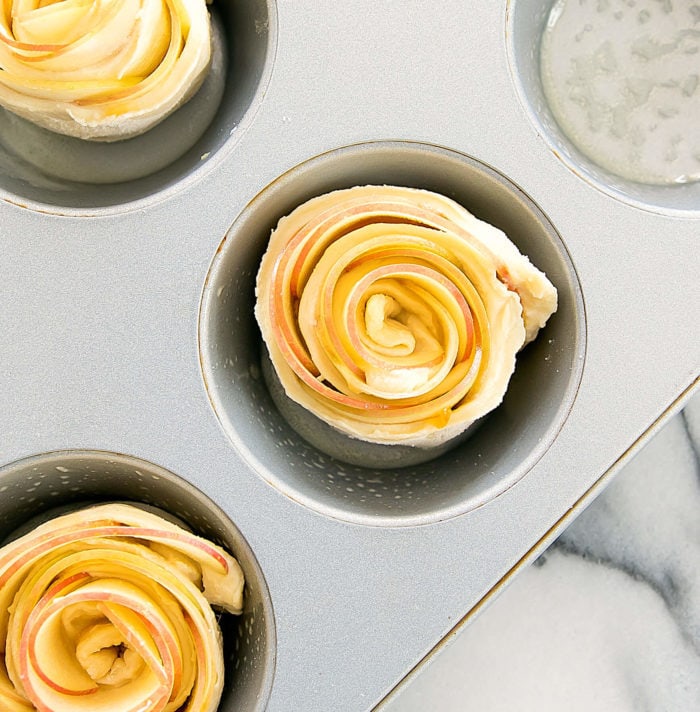 overhead photo of an unbaked Apple Rose Tart in a muffin tin