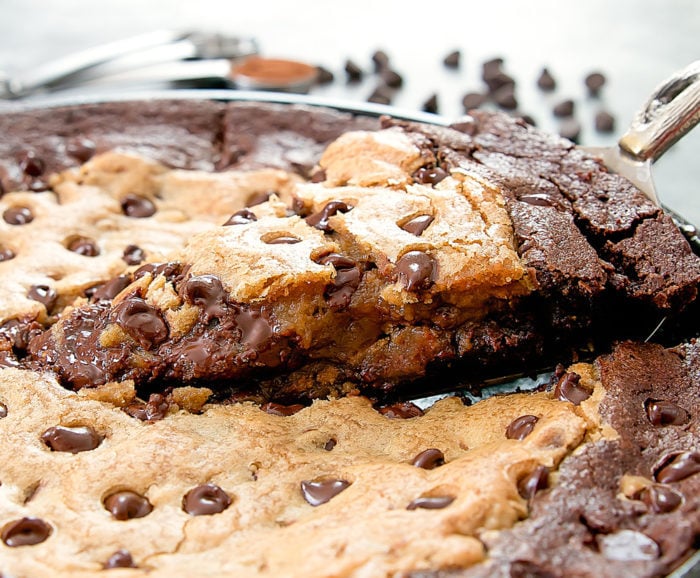 photo of a slice of Skillet Brownie Chocolate Chip Cookie being lifted out of the pan