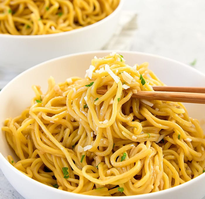 a close-up photo of chopsticks holding garlic noodles