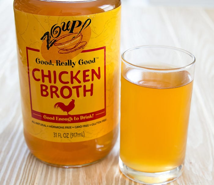 photo of a jar of Zoup! chicken broth with a glass of chicken broth next to it