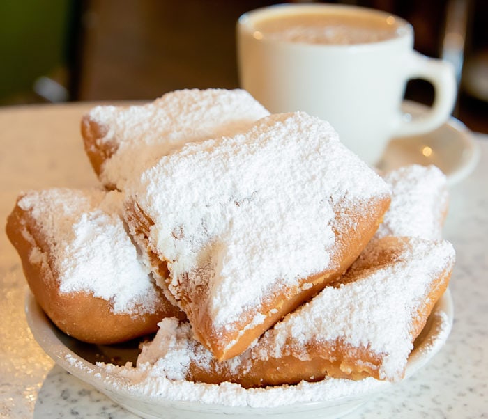 photo of a plate of beignets with coffee in the background