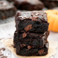 stack of 3 pumpkin brownies with brownies resting on cooling rack in background