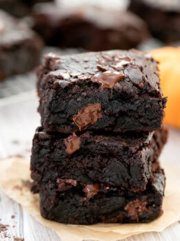 stack of 3 pumpkin brownies with brownies resting on cooling rack in background