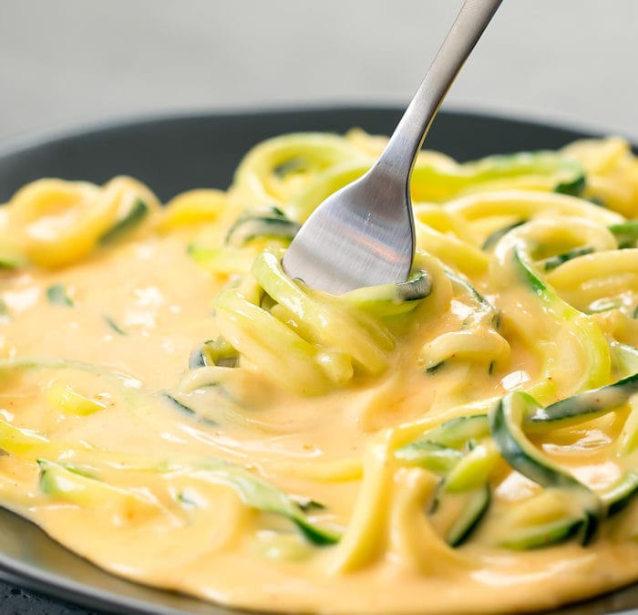 close-up photo of a fork twirling some zucchini noodles in cheese sauce