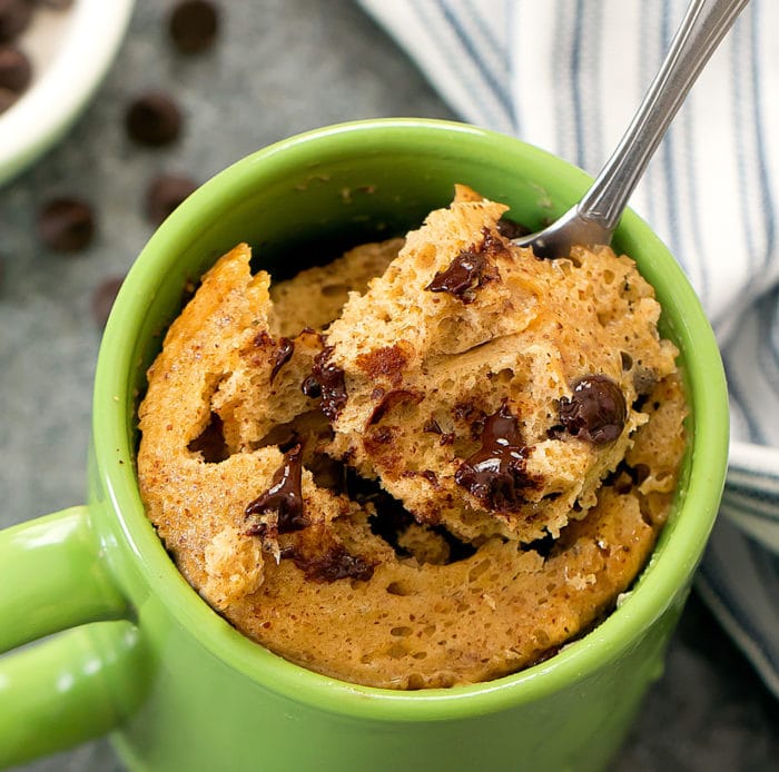 overhead photo of a Almond Butter Mug Cake with a spoon scooping out a bite of cake