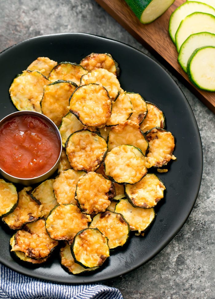 overhead photo of parmesan zucchini crisps on a plate with dipping sauce