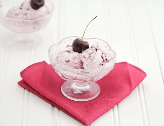 photo of cherry ice cream served in ice cream bowl with fresh cherry on top