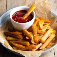 photo of a plate of french fries with a bowl of ketchup