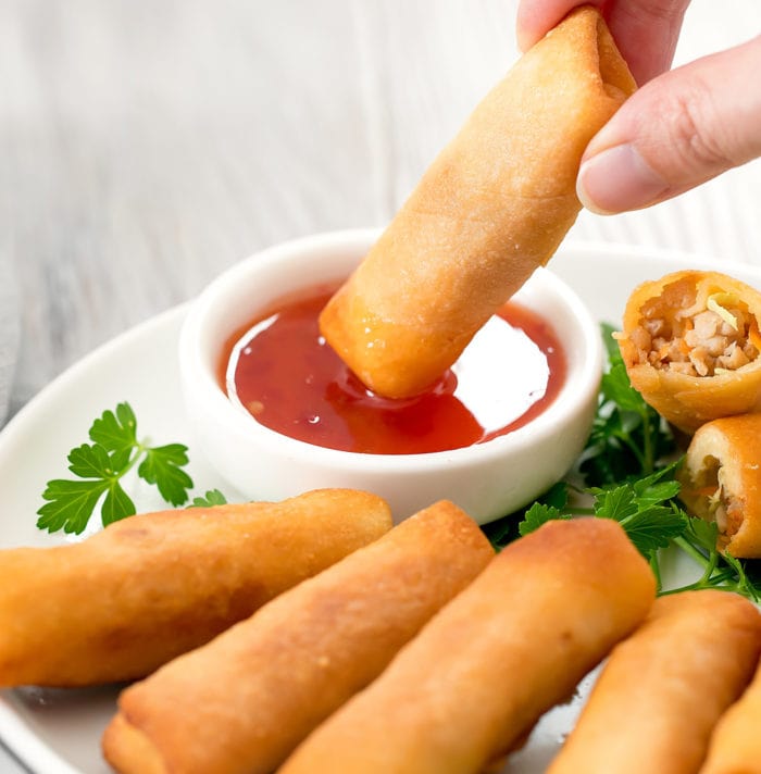 photo of an egg roll being dipped in sauce