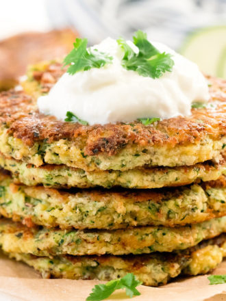 photo of a stack of zucchini fritters with sour cream