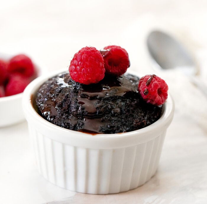  a small chocolate cake topped with raspberries.