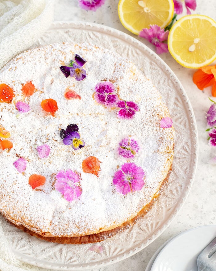 overhead photo of the cake dusted with powdered sugar and decorated with flowers.