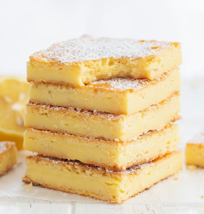 a stack of lemon brownies with a bite taken out of the one on top.