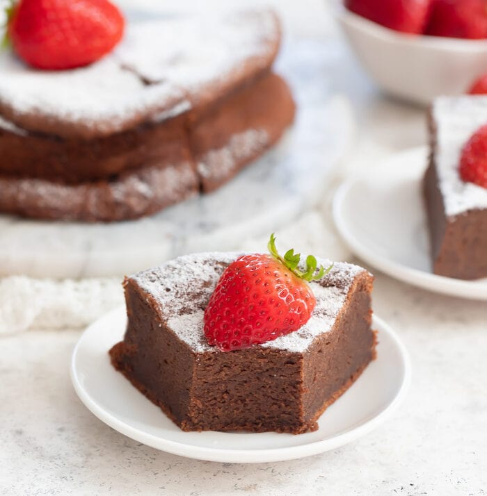 a slice of cake dusted with powdered sugar and garnished with a strawberry on top.