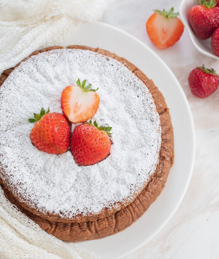 overhead shot of the cheesecake dusted with powdered sugar and garnished with strawberries.