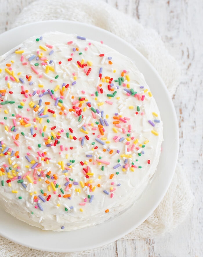 a frosted vanilla cake topped with sprinkles.