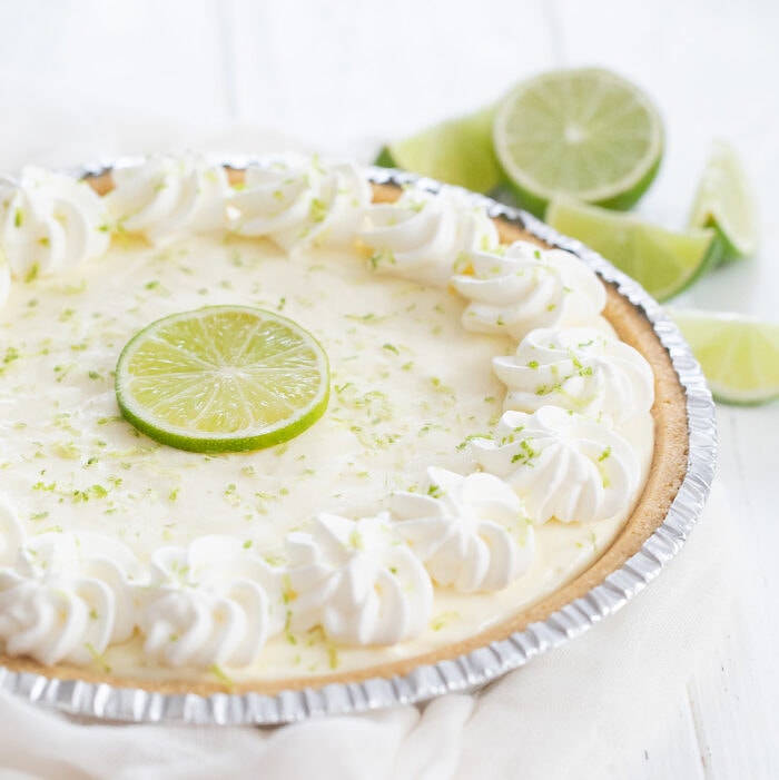 a whole key lime pie garnished with whipped cream and a lime slice.