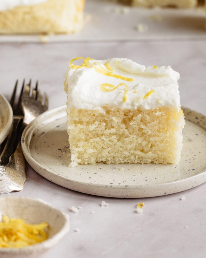 a slice of frosted lemon cake on a plate.