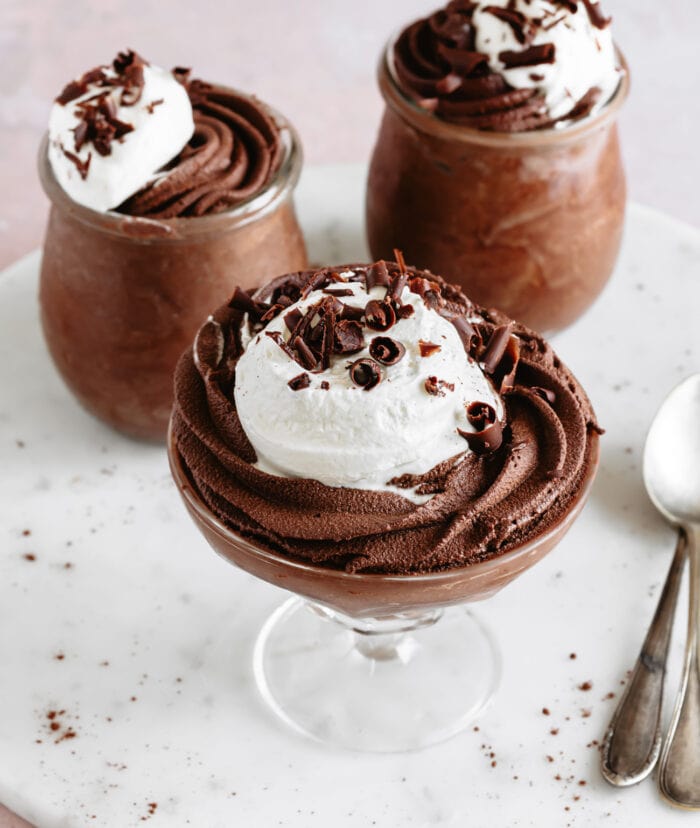 two servings of mousse in jars and one serving in a glass.