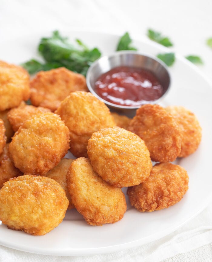 chicken nuggets on a plate with a small bowl of ketchup.