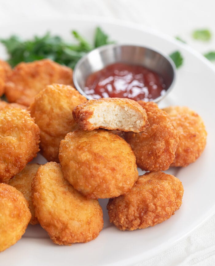 a plate of chicken nuggets with a bite taken out of one.