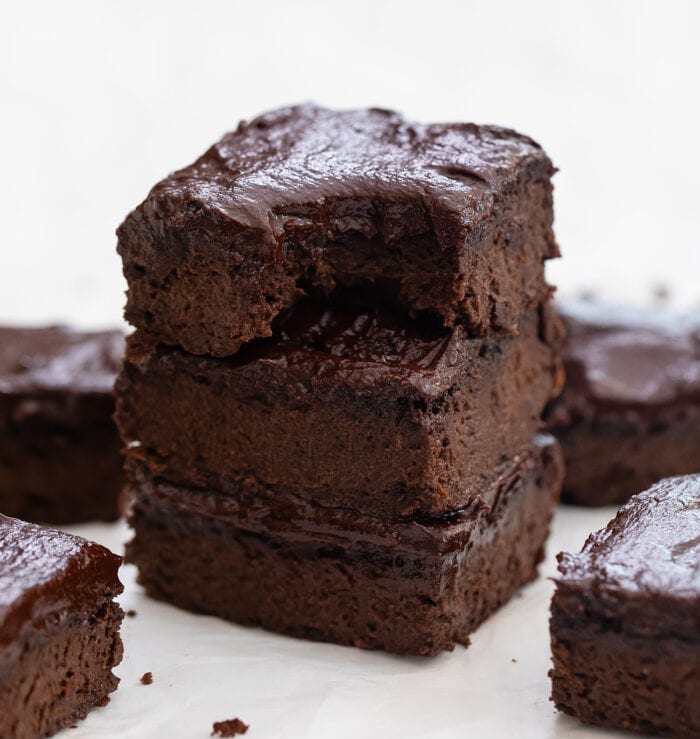 a stack of brownies with the top one with a bite taken out of it.
