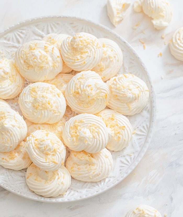 coconut cloud cookies stacked on a plate.