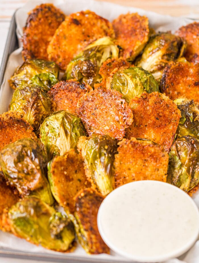 a plate of crispy parmesan brussels sprouts with a bowl of dip.