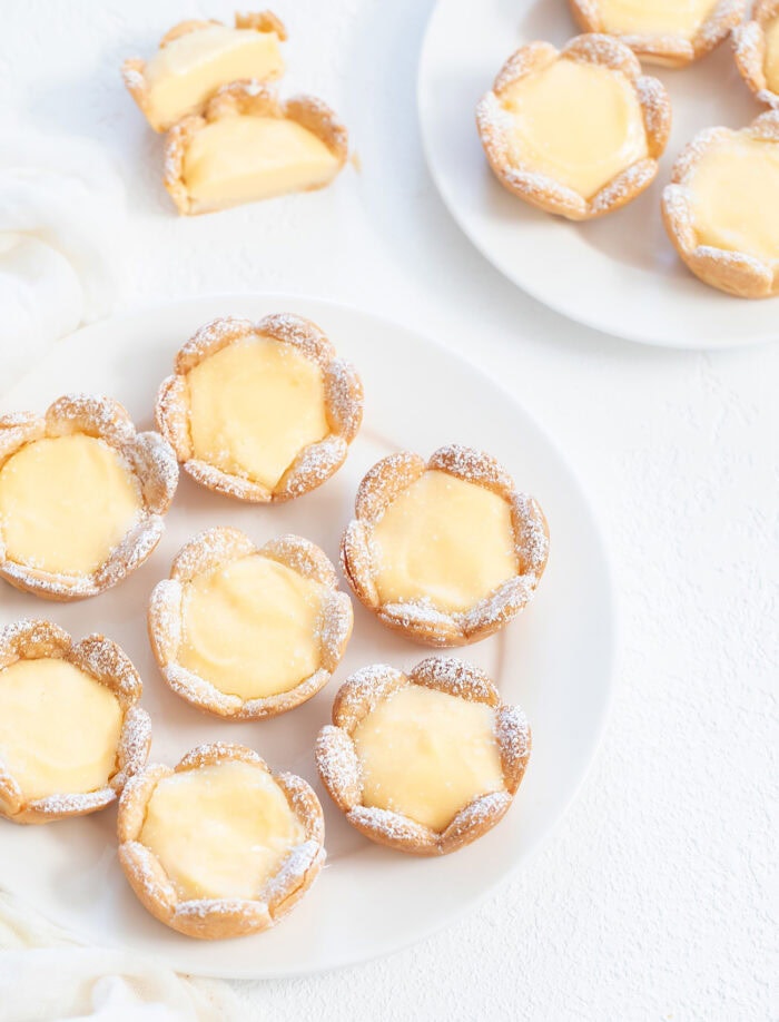 Lemon pies on a white plate dusted with powdered sugar