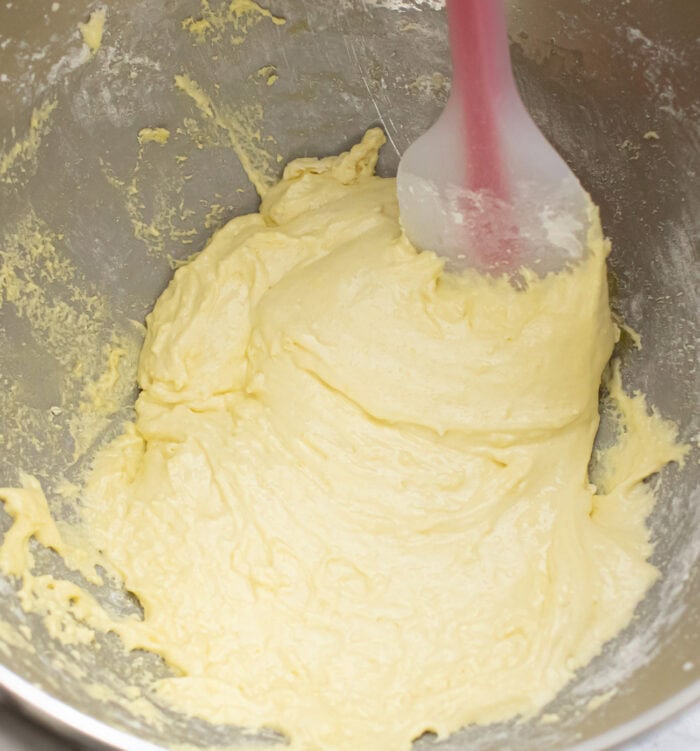 Cake batter in a mixing bowl with a silicone spatula