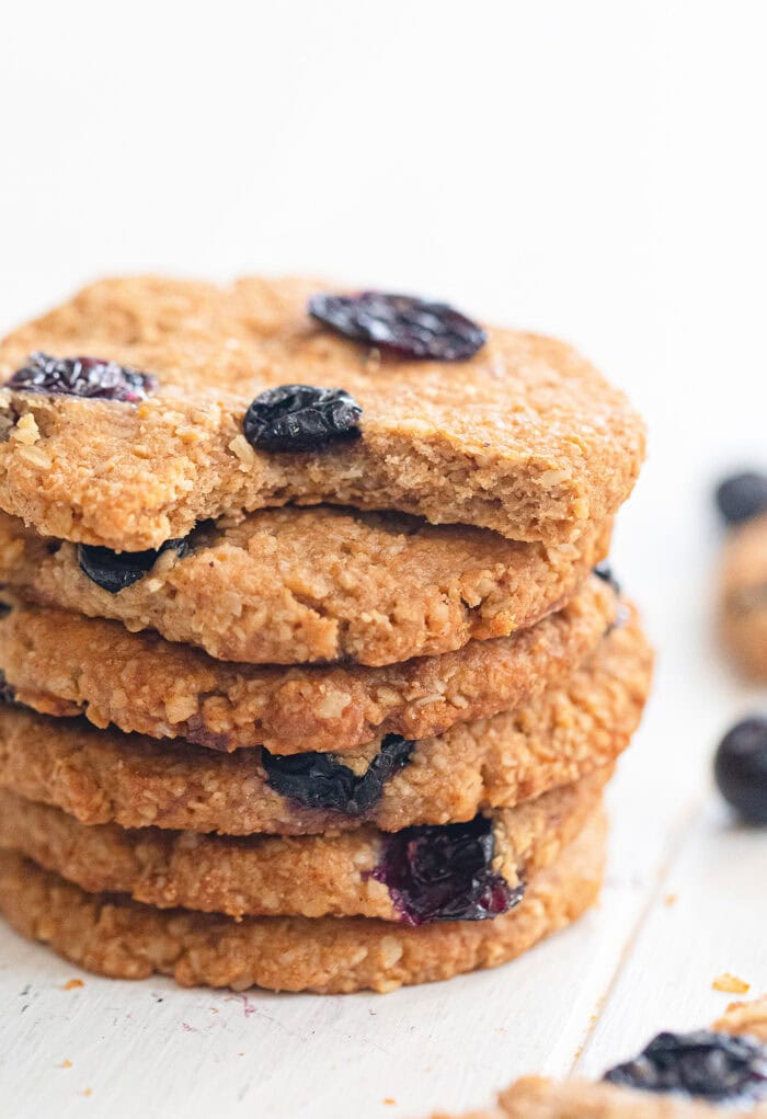A stack of crispy blueberry oatmeal cookies with a bite taken out of one
