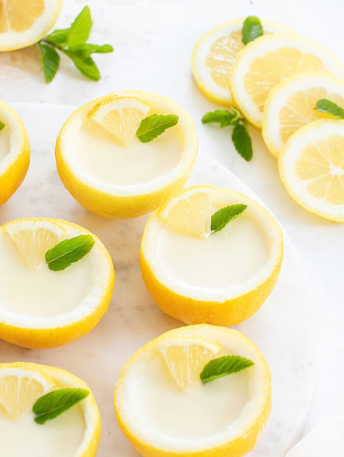 Lemon posset desserts with thick cream, a lemon wedge and garnish