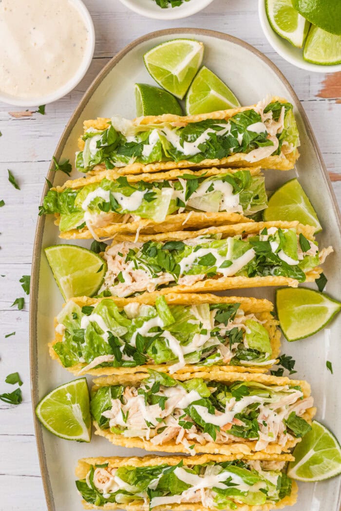 Chicken tacos on an oval serving dish with lime wedges