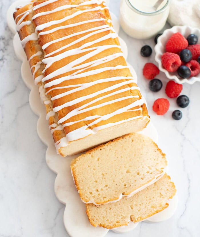 French yogurt cake with two slices cut and a side of berries in a cup